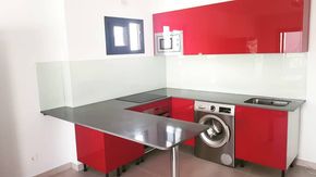 Una cocina con armarios rojos y lavadora.