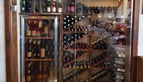 Una bodega llena de muchas botellas de vino y un refrigerador.