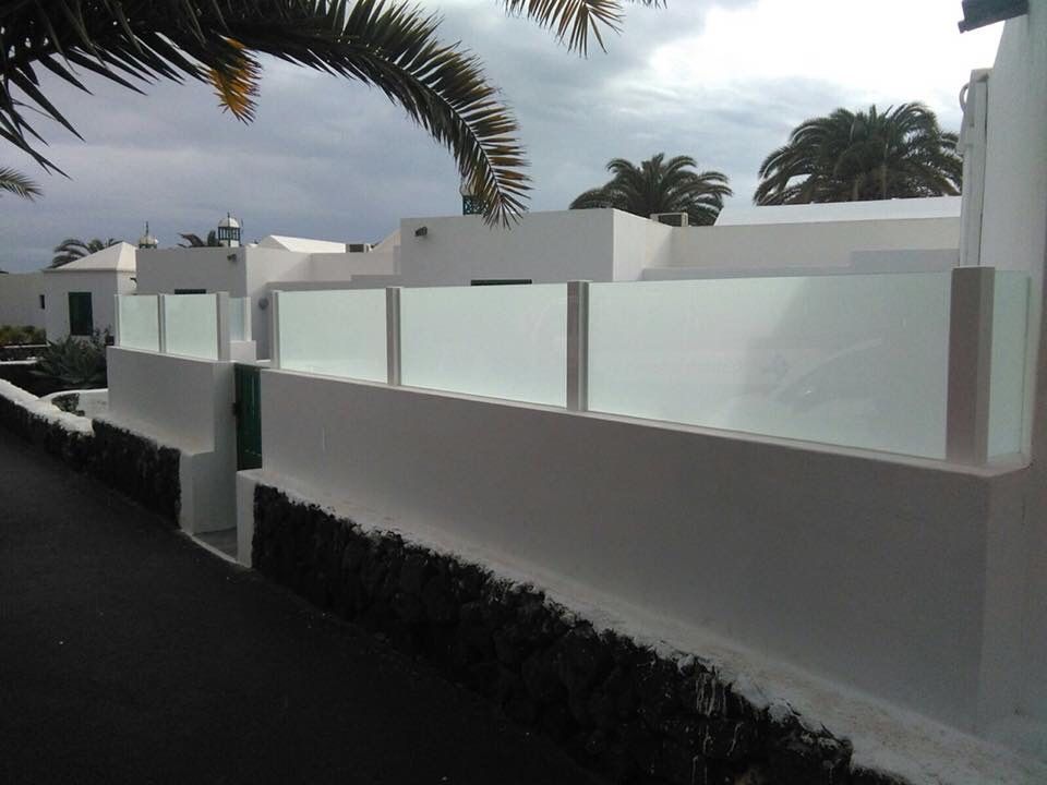 Una valla blanca con una palmera al fondo.