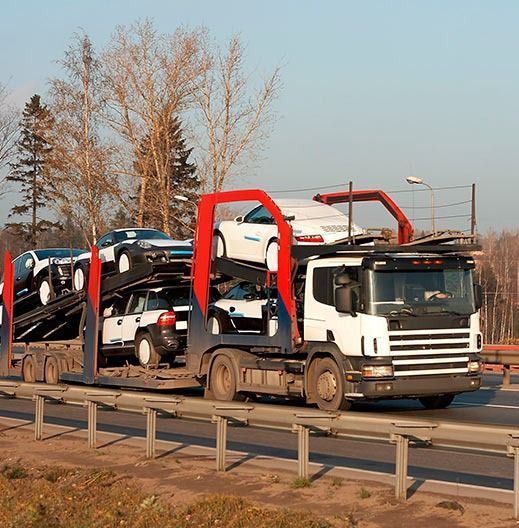 Un camión transporta automóviles en un remolque por una carretera.