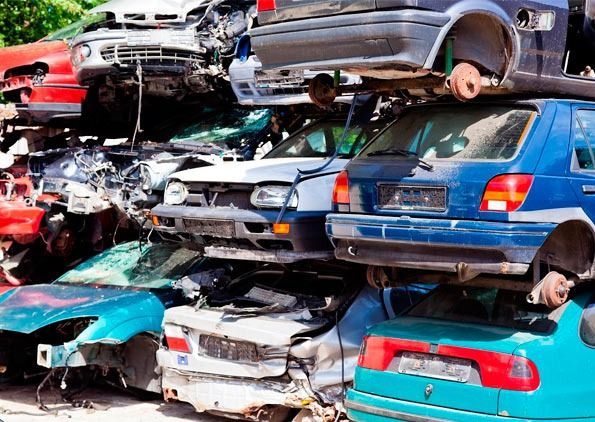 Un montón de coches están apilados uno encima del otro en un depósito de chatarra.