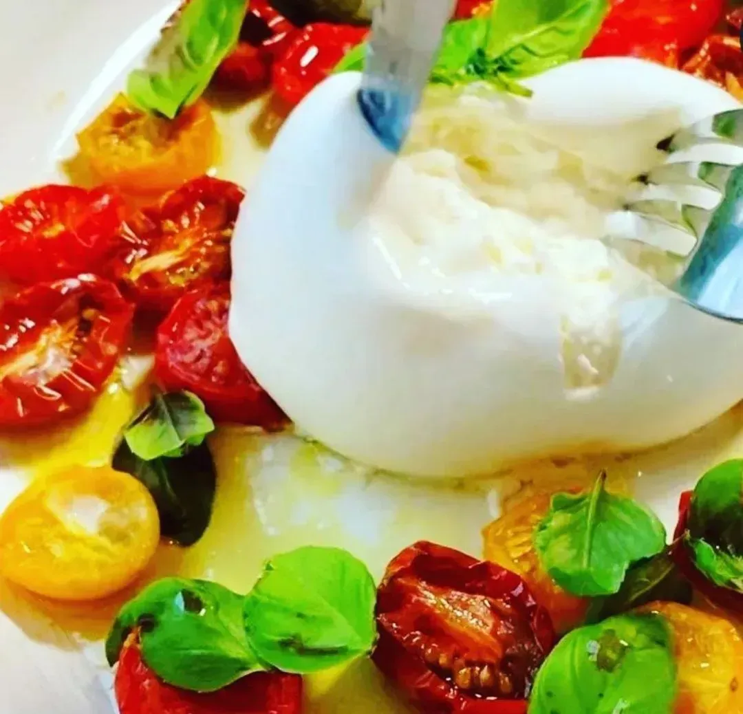 Un plato de comida con tomates y mozzarella y un tenedor.