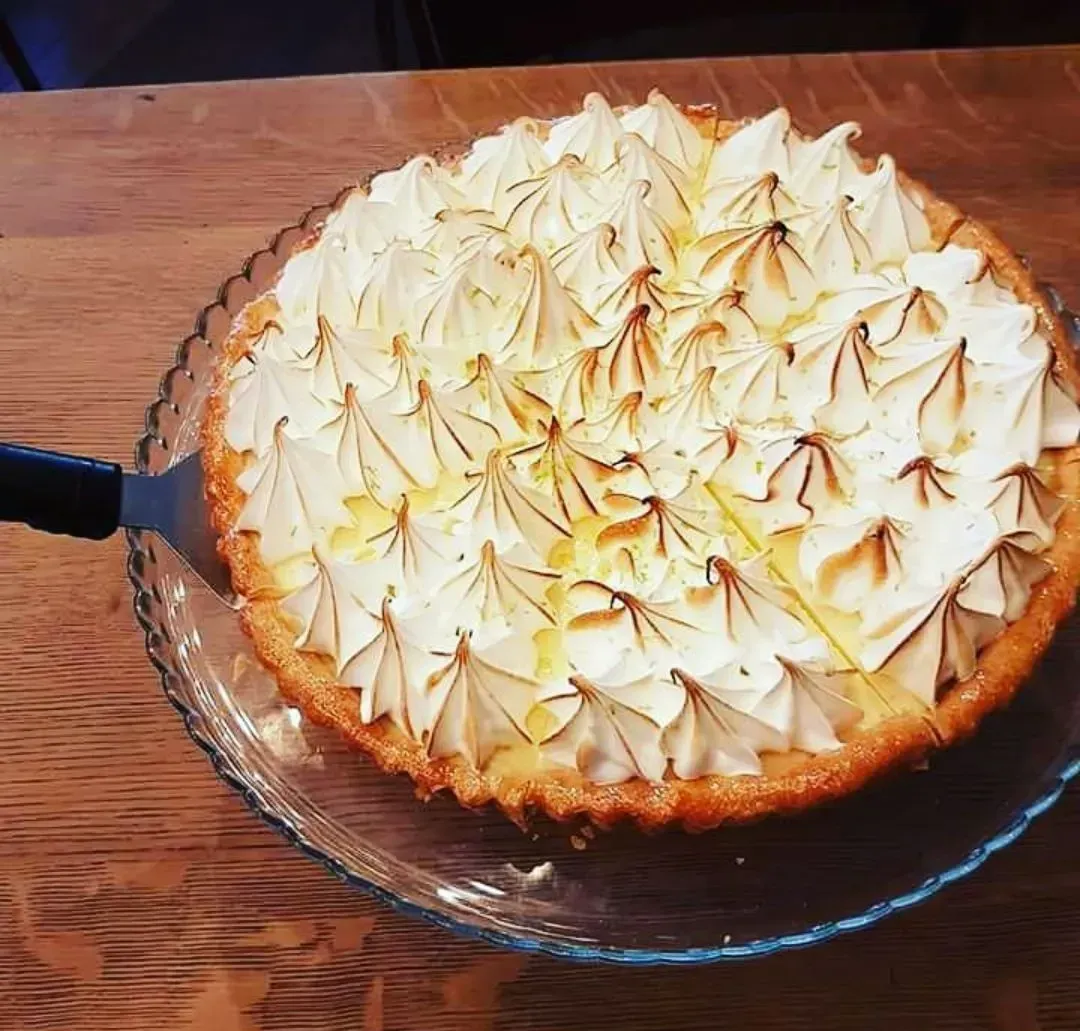 Un pastel con crema batida encima está en un plato de vidrio.
