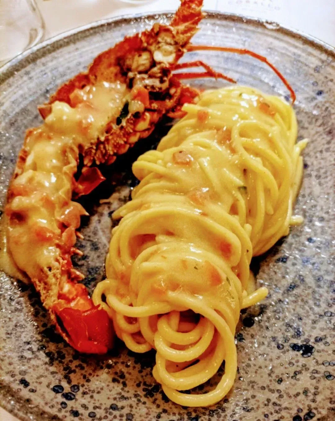 Un plato de espaguetis con una langosta encima