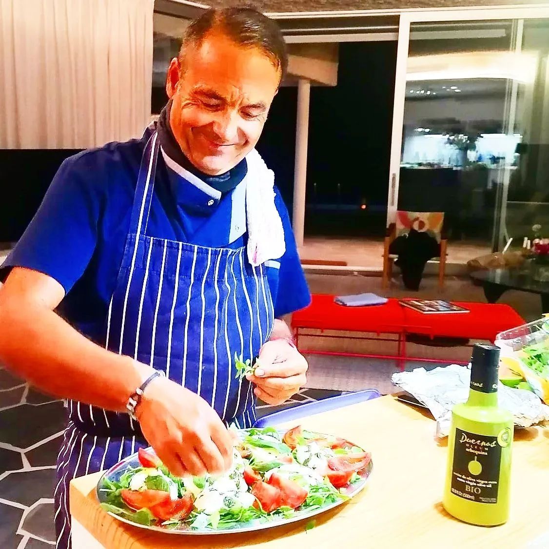 Un hombre con delantal está preparando comida en una tabla de cortar.