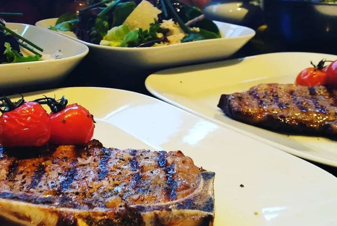 Un filete con tomates encima en un plato.