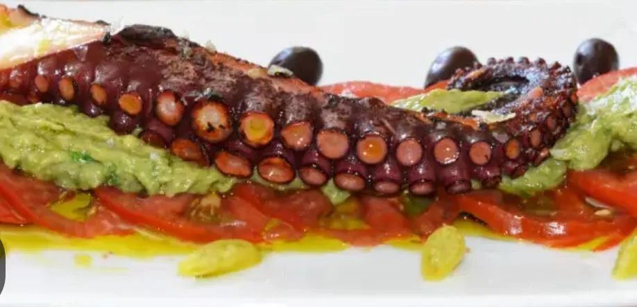 Un primer plano de un plato de comida con un pulpo encima.
