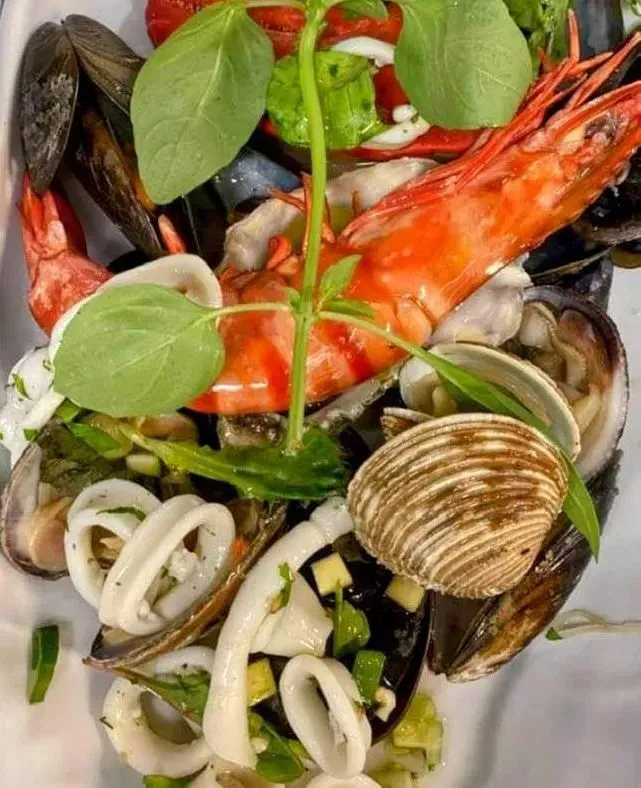 Un primer plano de un plato de mariscos que incluye camarones, mejillones y calamares.