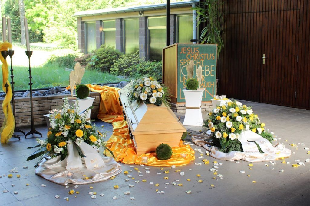 Trauerdekoration mit Blumen, Lichtern und Tüchern, vorbereitet für eine Abschiedszeremonie im Freien.