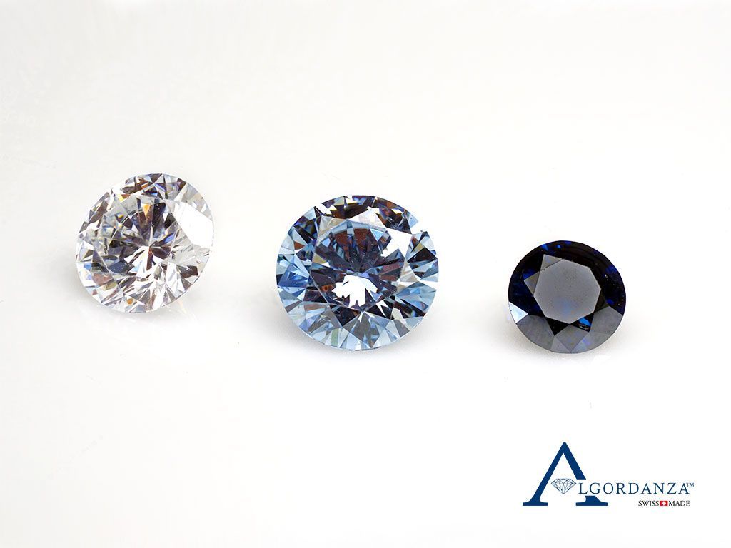 Drei lose Diamanten in verschiedenen Farben und Schliffen, auf weißem Hintergrund arrangiert.