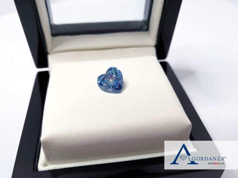 Kleiner blauer Erinnerungsdiamant in einer geöffneten Schmuckschatulle auf hellem Polster.