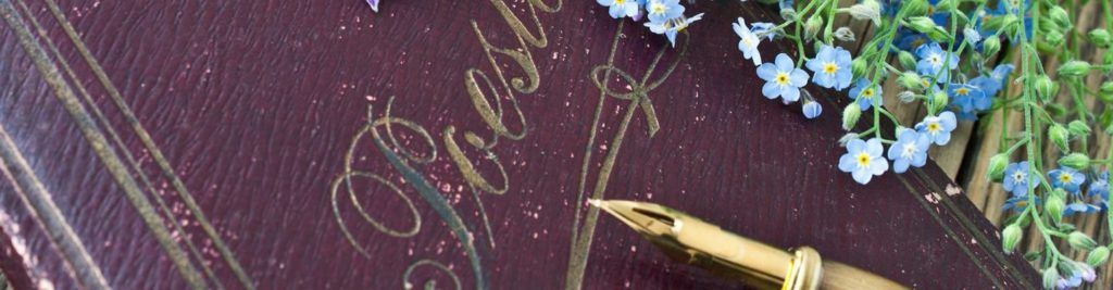Nahaufnahme von „Poesie“ in Goldschrift auf Papier mit Füllfeder, dekoriert mit kleinen Blüten.