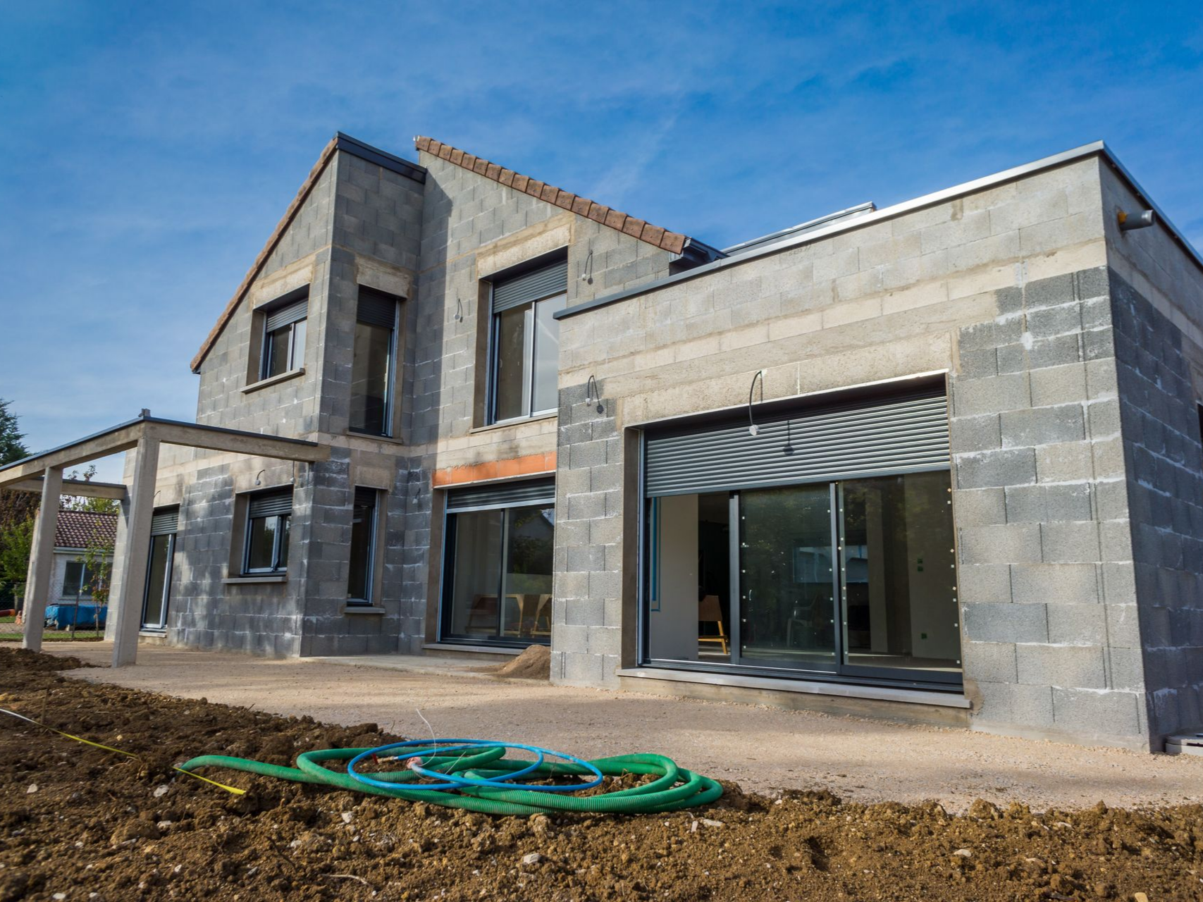 Maison en construction avec murs en parpaings gris.