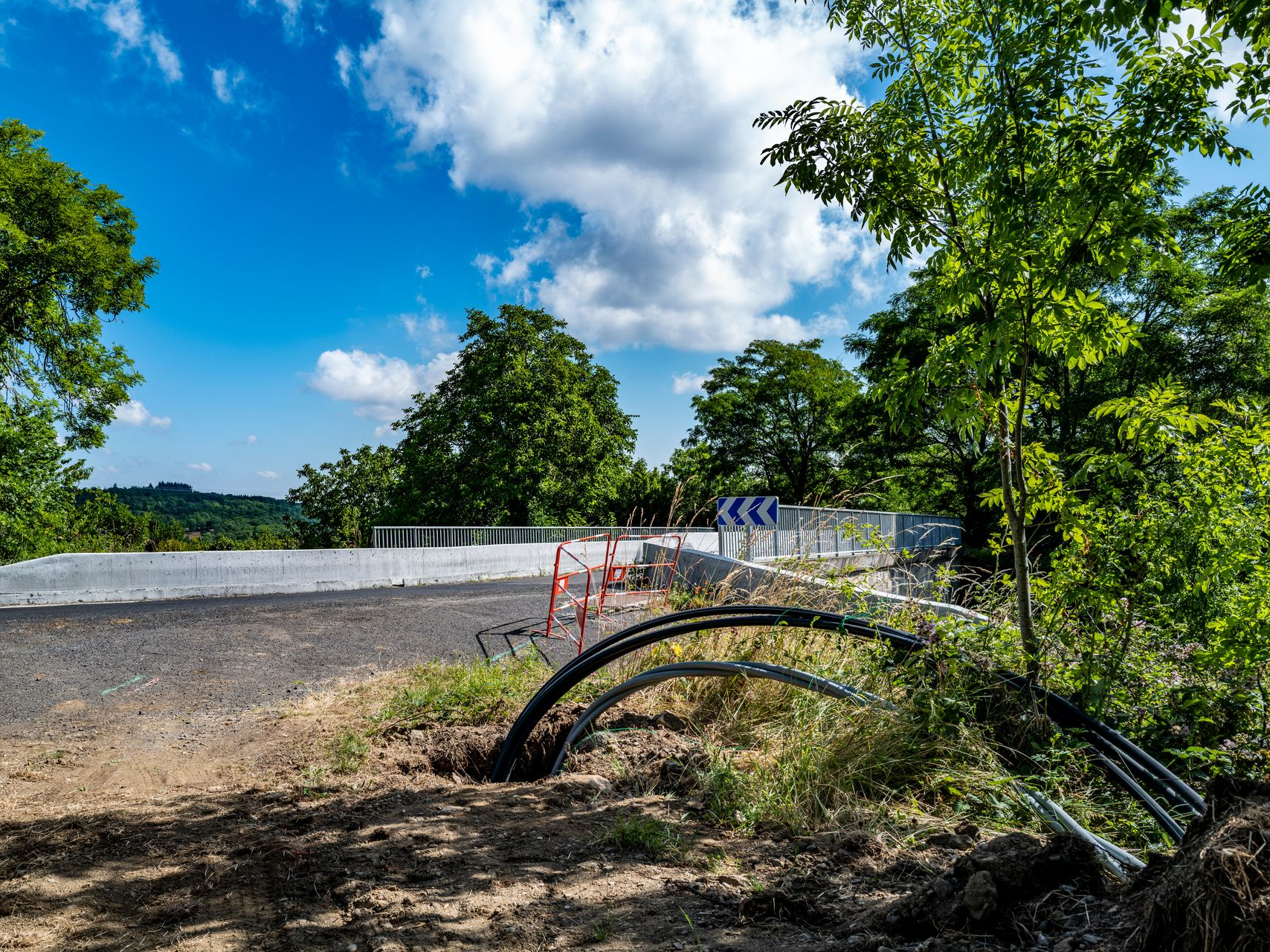 Route avec câbles apparents, cônes de signalisation.