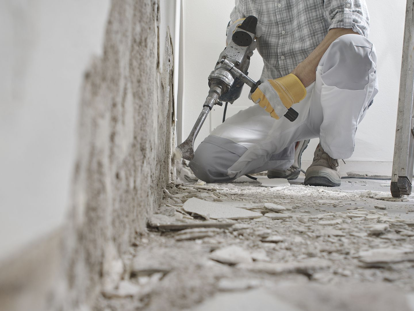 Une personne utilise un marteau-piqueur pour enlever des matériaux.