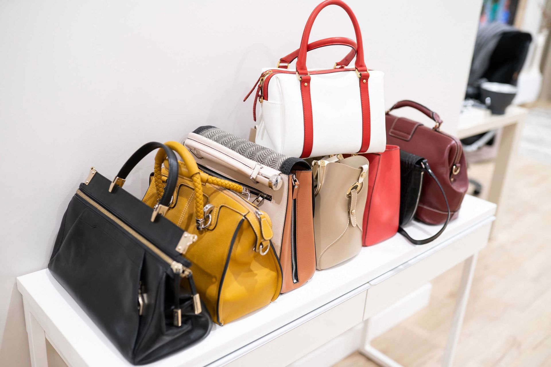 Un montón de bolsos están apilados uno encima del otro sobre una mesa.