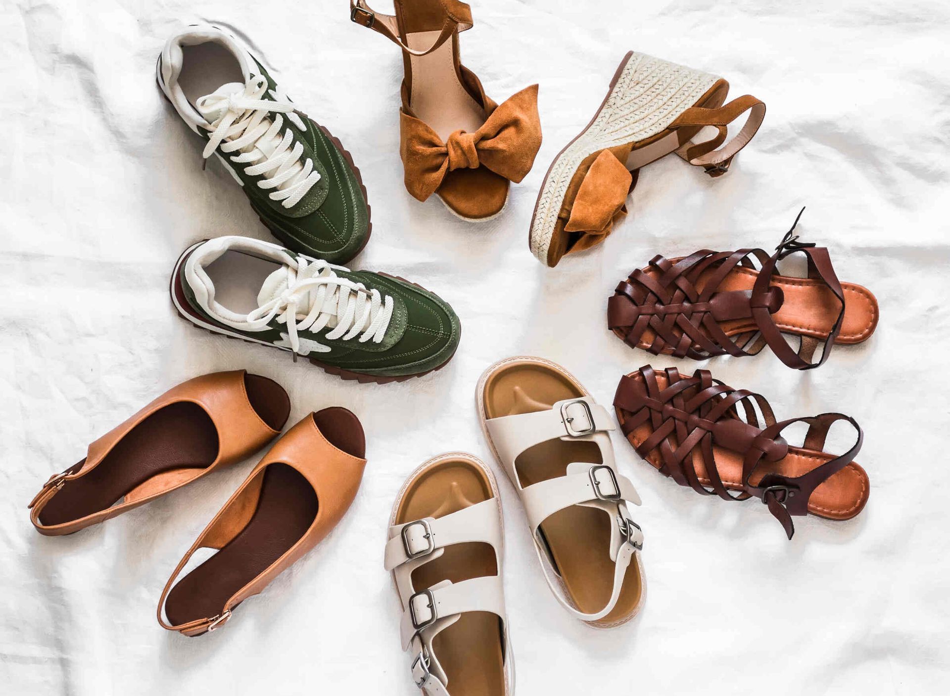 Una variedad de zapatos están dispuestos en círculo sobre una cama.