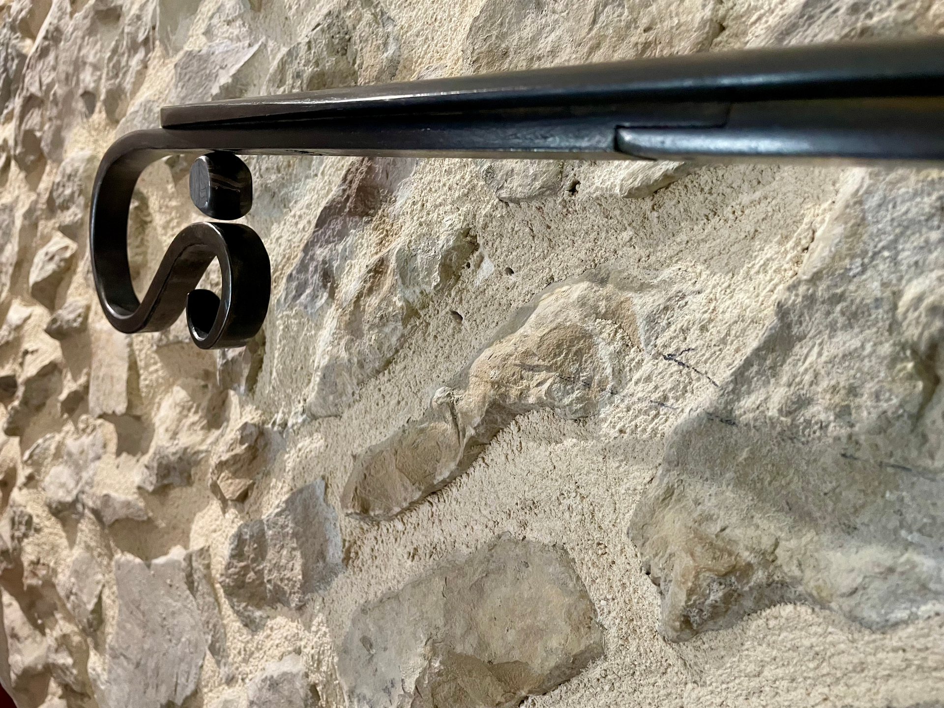 Une rampe noire sur un mur en pierre