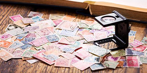 Différents timbres posés sur une table et loupe spécialisée