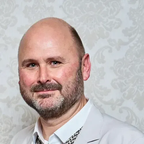 Un hombre calvo con barba sonríe