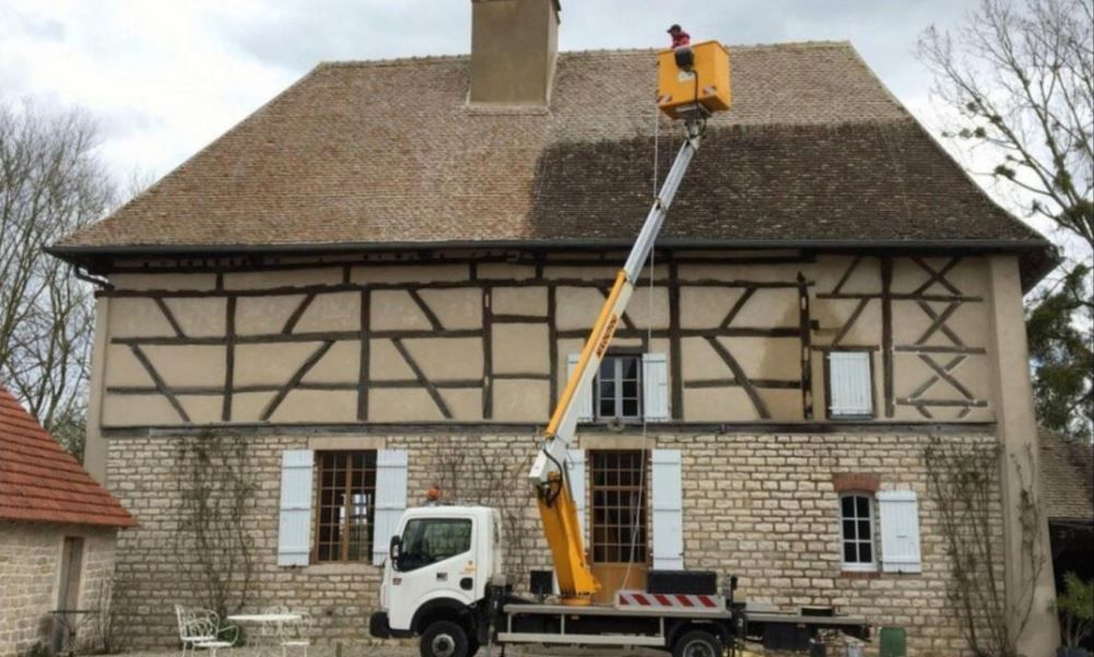 Véhicule avec nacelle devant une maison