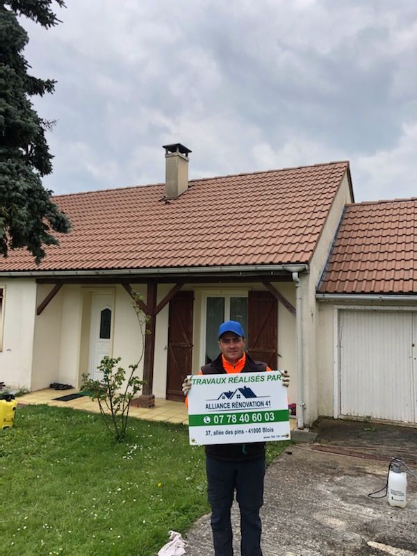 Employé de l'entreprise tenant une pancarte publicitaire devant une maison nettoyée