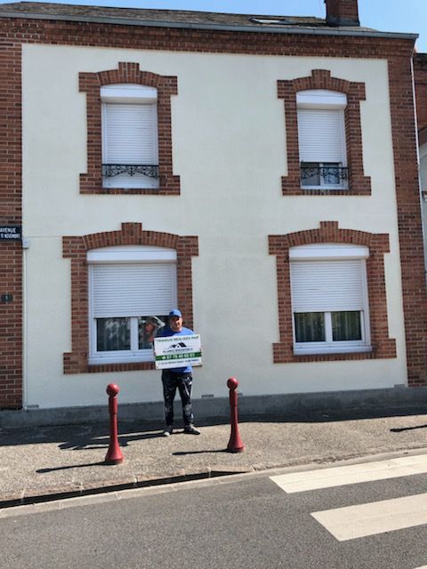 Employé de l'entreprise tenant une pancarte publicitaire devant une maison repeinte