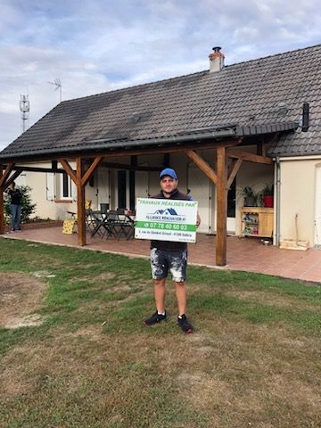 Employé de l'entreprise devant une maison tenant une pancarte publicitaire