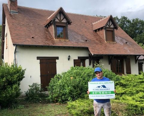 Employé d'alliance rénovation 41 devant une maison tenant une pancarte publicitaire