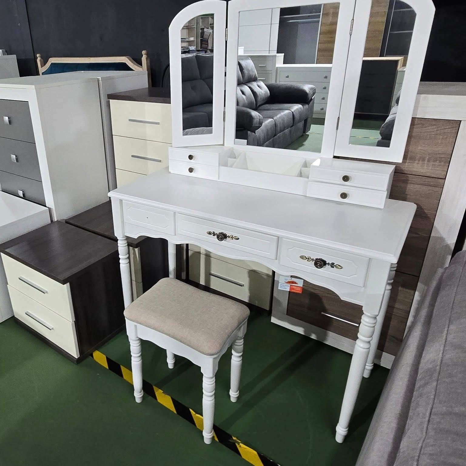 Un tocador blanco con tres espejos y un taburete.