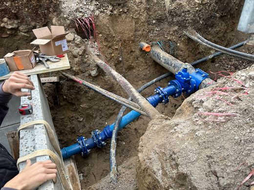 Des ouvriers installent des canalisations souterraines bleues dans une tranchée.