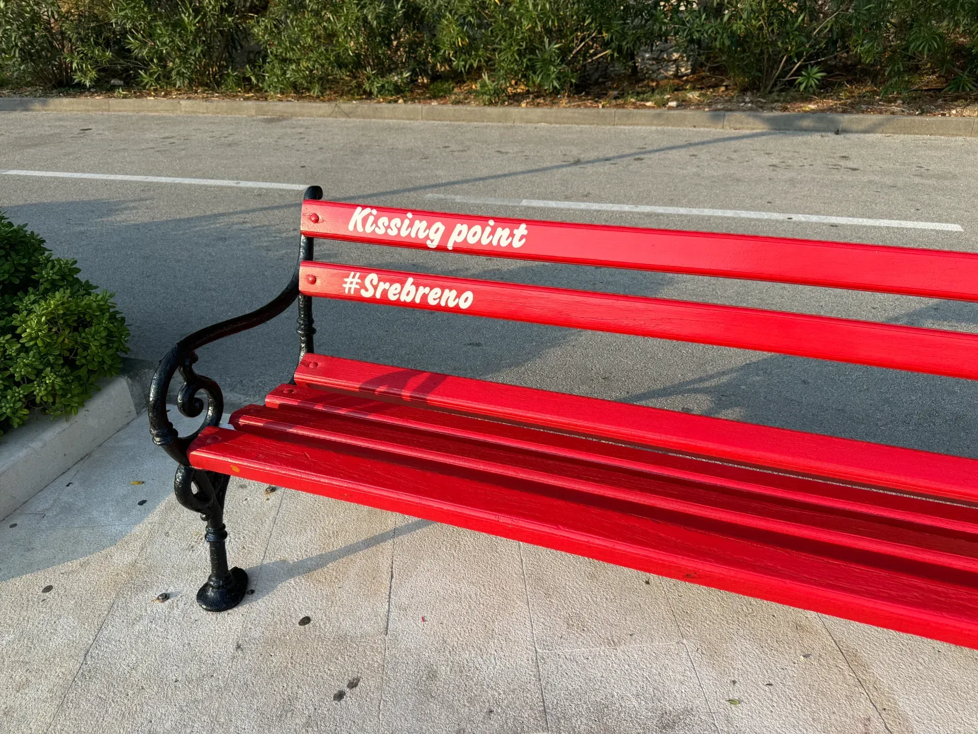A bright red park bench outdoors with the words