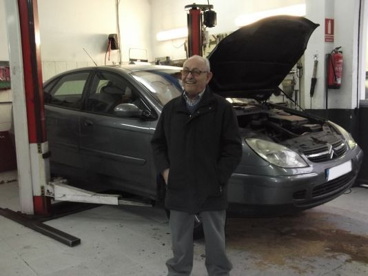 Un hombre se encuentra frente a un automóvil con el capó levantado.