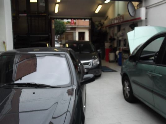 Dos coches están aparcados en un garaje con el capó abierto.