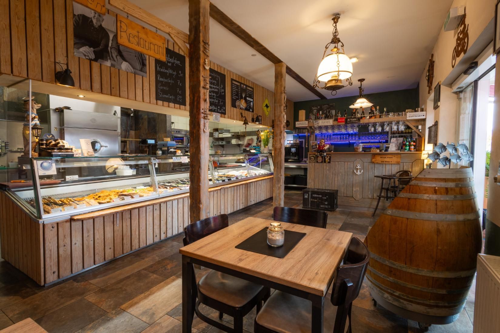 Ein Fischrestaurant mit Tischen und Stühlen und einem Fass in der Mitte des Raumes.