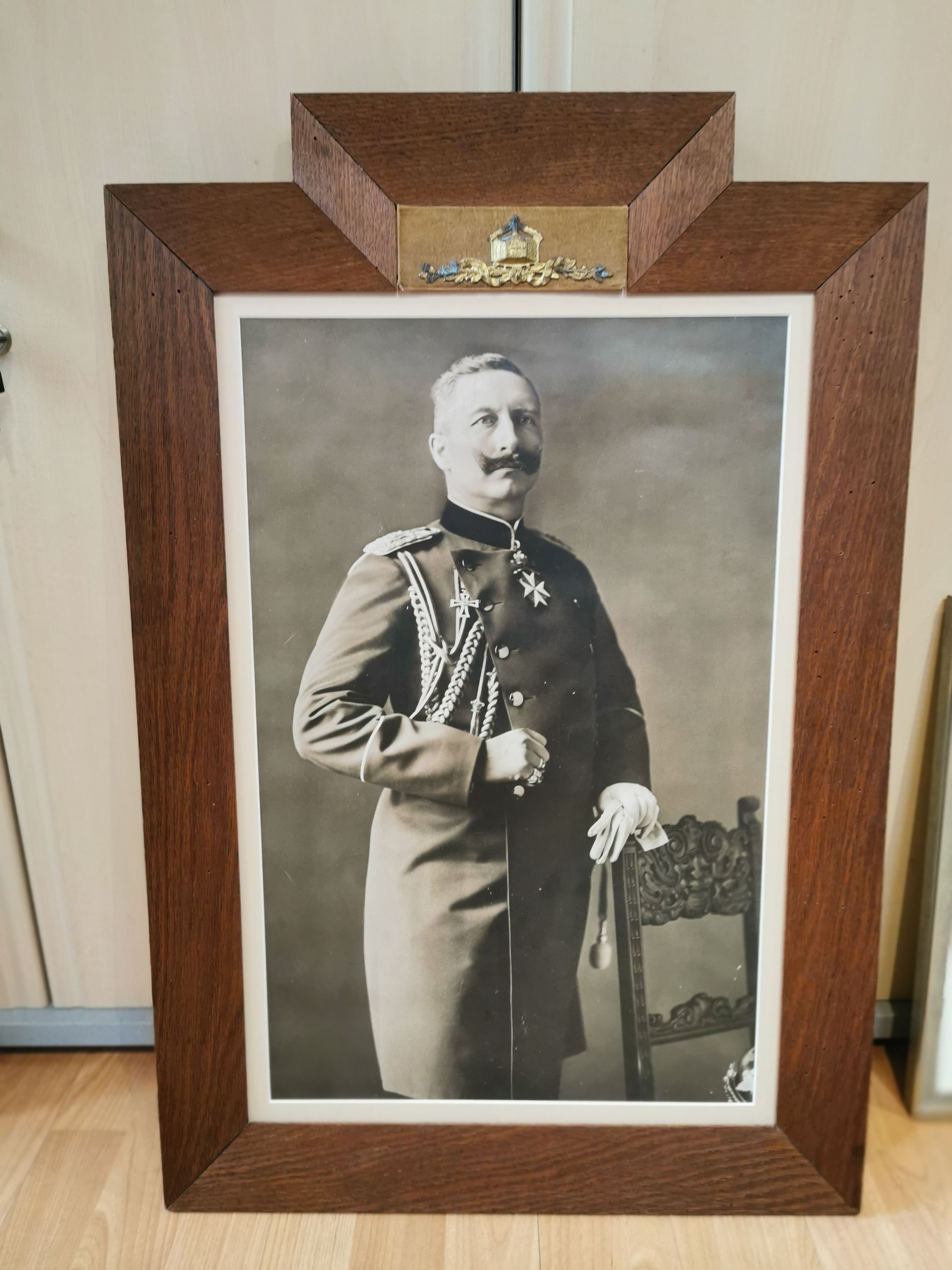 Sepiafarbenes Porträt eines Mannes in formeller Militäruniform in einem Holzrahmen mit dekorativer Zierplakette.