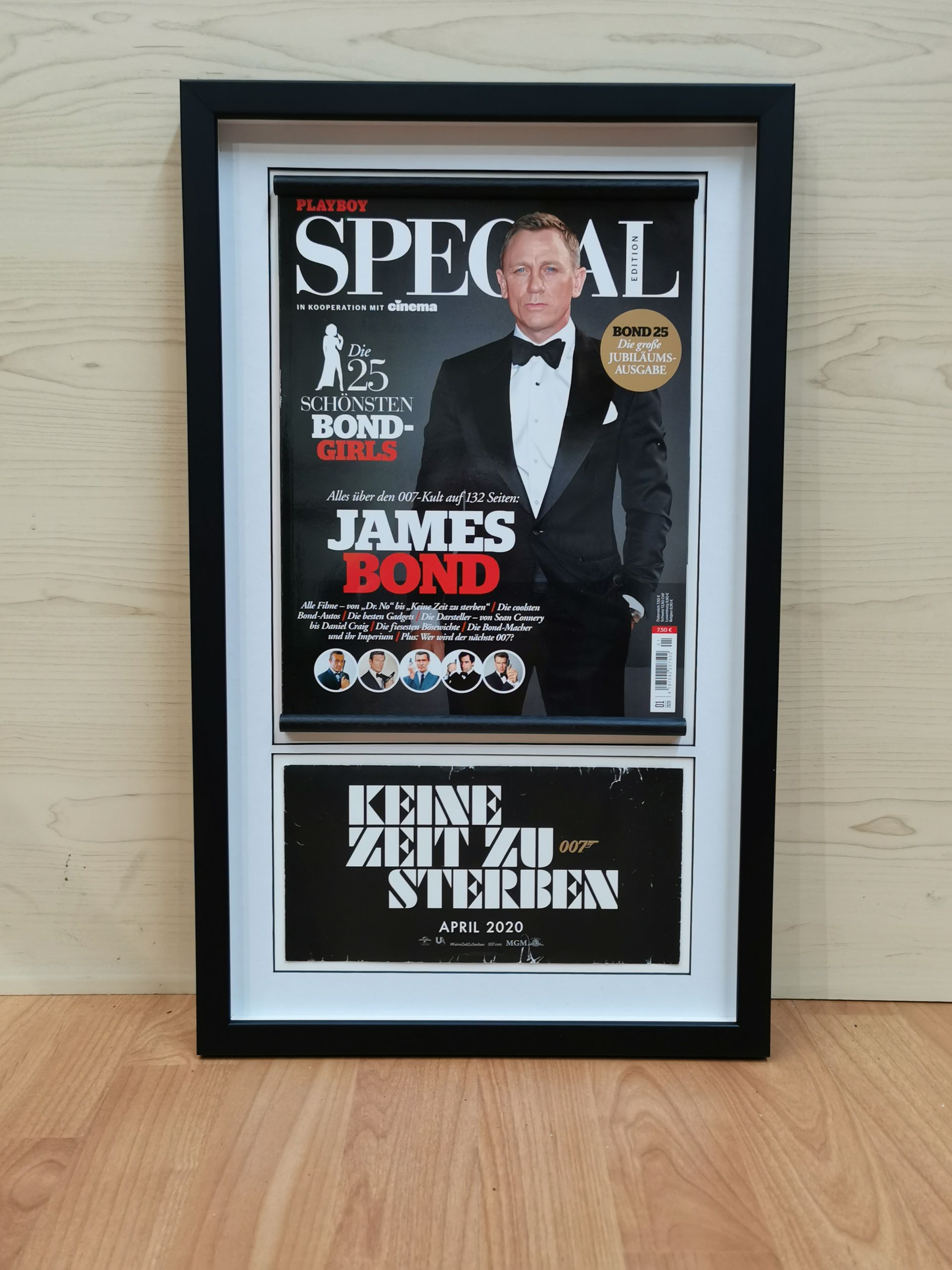 Ein gerahmter James-Bond-Sondermagazin-Coverdruck lehnt an einer Wand auf einem Holzboden.
