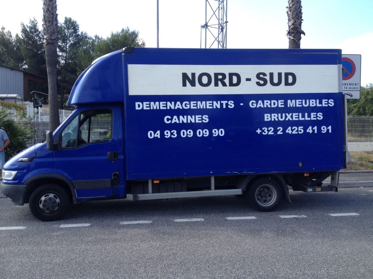 Camion de déménagement bleu avec le logo « NORD-SUD », les numéros de téléphone et les adresses Cannes et Bruxelles.