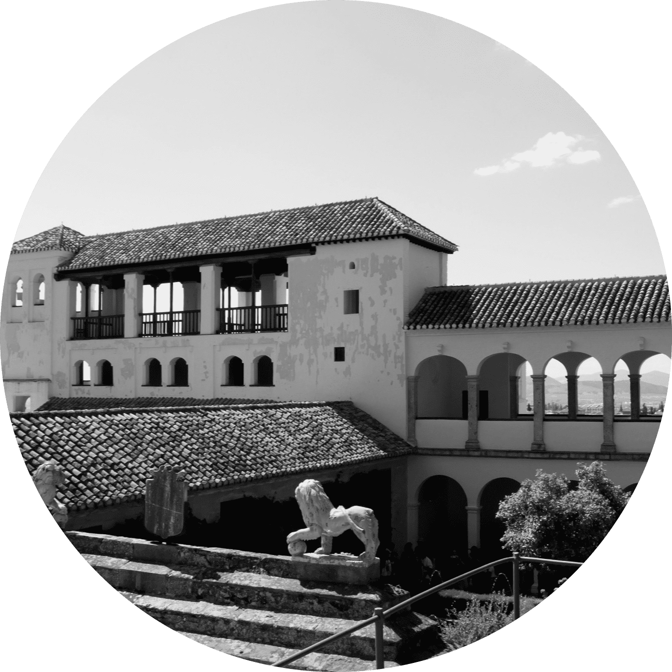 Fotografía en blanco y negro de un edificio con balcón, arcos y una estatua, probablemente en España.