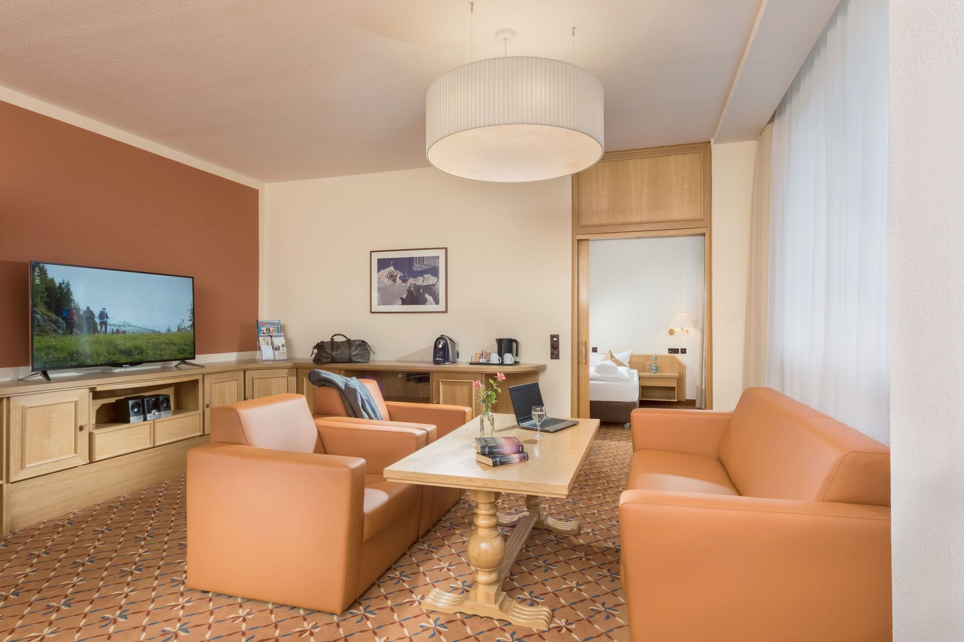 Ein Wohnzimmer mit Couch, Stühlen, Tisch und Fernseher.