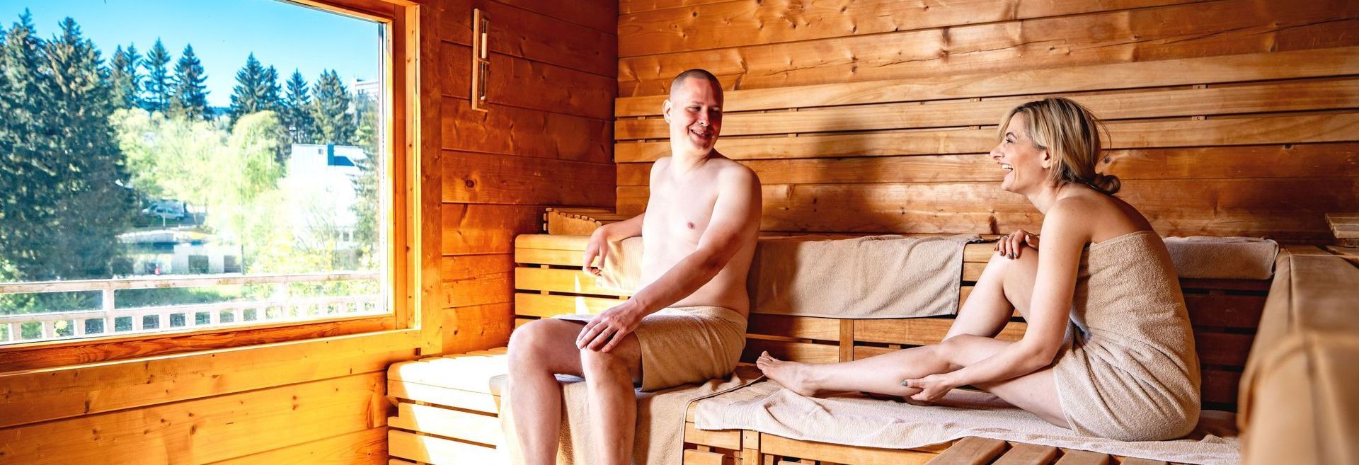 Ein Mann und eine Frau sitzen in einer Holzsauna.