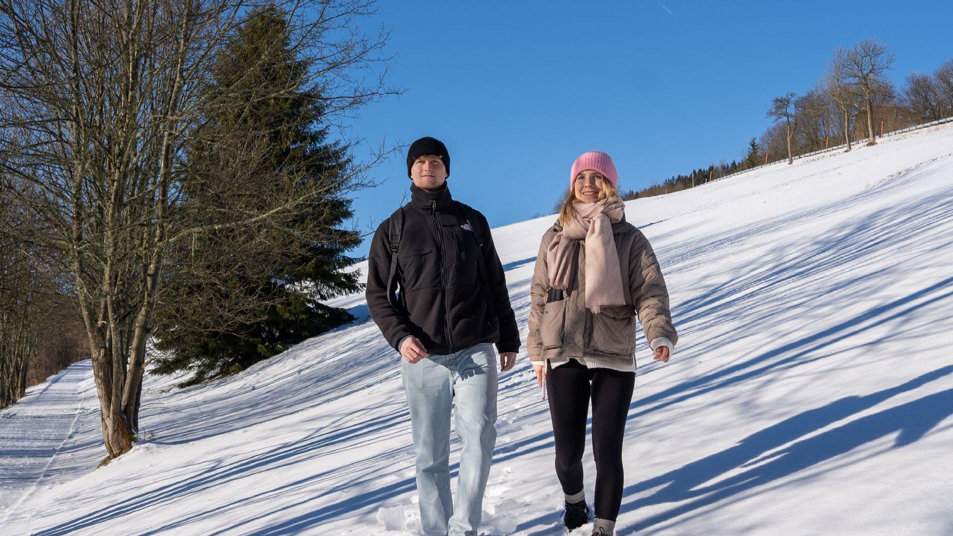 Ein Mann und eine Frau gehen im Schnee spazieren.