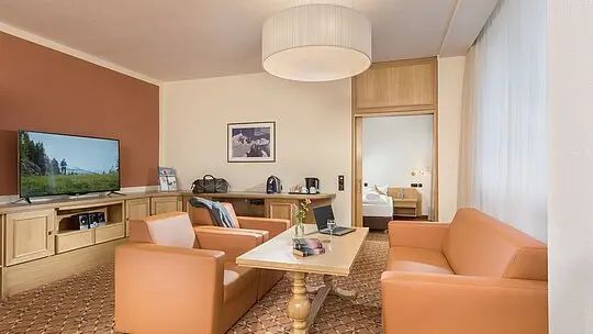 Modernes Wohnzimmer mit pfirsichfarbenen Sesseln, Fernseher, Couchtisch und dezenter, neutraler Dekoration