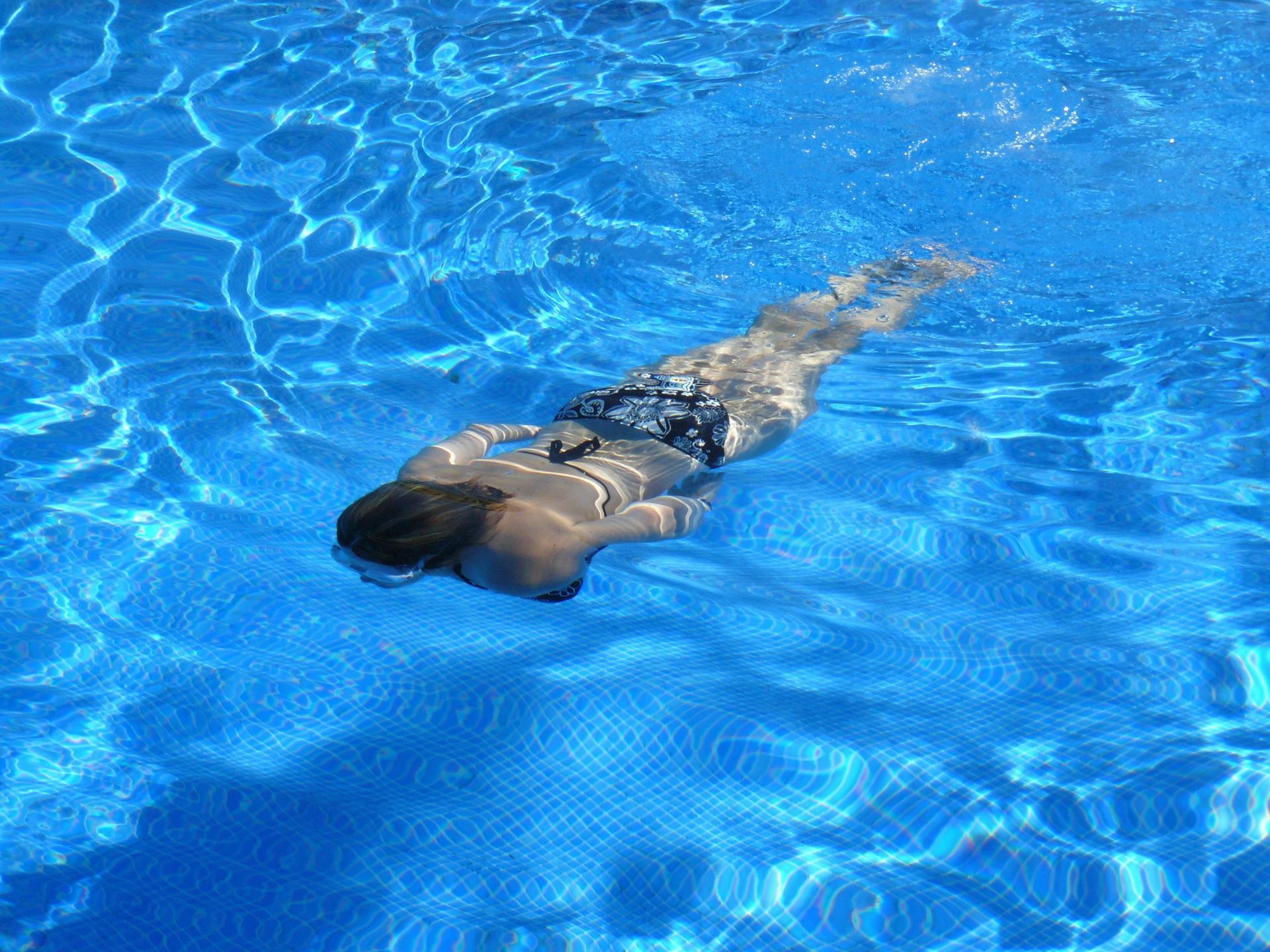Eine Frau schwimmt unter Wasser in einem Schwimmbecken.