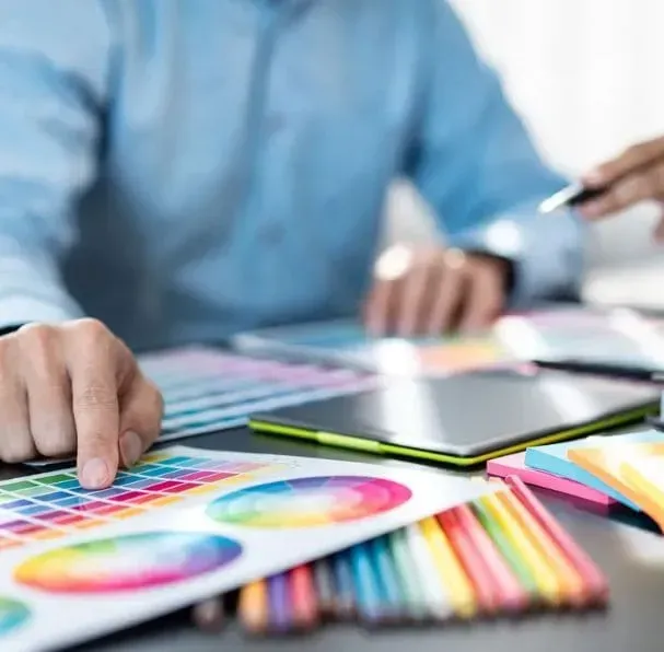 Person pointing to color palette during a design discussion at a desk.