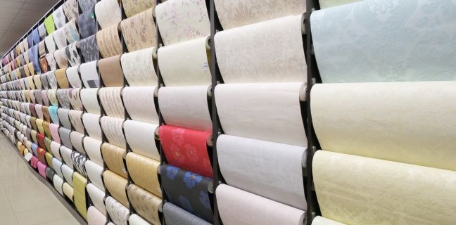 A wall display of rolled wallpaper samples in various colors and patterns.