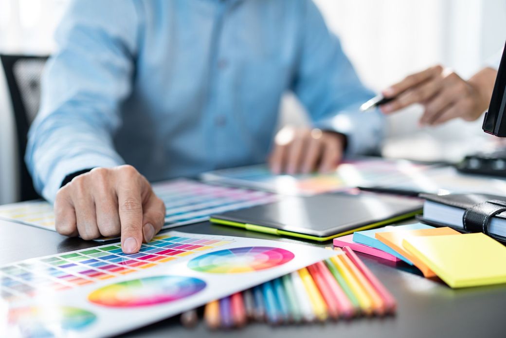 Person pointing to color palette during a design discussion at a desk.