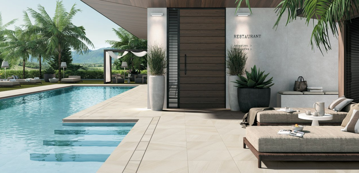 Terrasse moderne au bord de la piscine avec chaises longues, verdure et un élégant coin salon couvert.