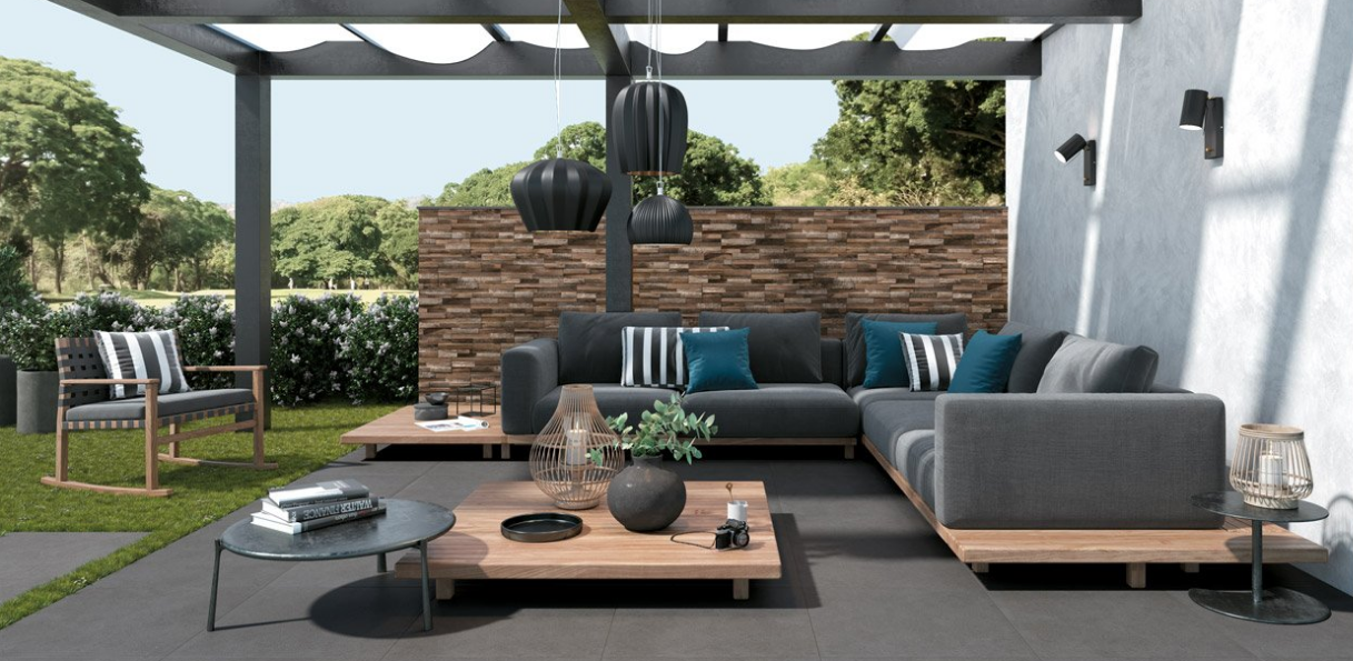 Terrasse extérieure moderne avec canapé d'angle gris, table basse, pergola et cheminée en briques