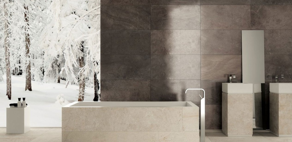 Salle de bains moderne et minimaliste avec baignoire en pierre, mur sombre et vue sur la forêt enneigée à travers une grande fenêtre
